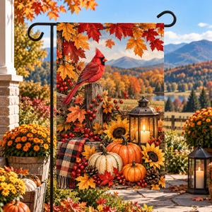 May include: A decorative garden flag featuring a vibrant red cardinal perched on a wooden post, surrounded by autumn maple leaves, pumpkins, sunflowers, a plaid blanket, and a lantern, set against a scenic mountain landscape background.