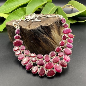 Può includere: Una collana importante a più fili caratterizzata da numerose pietre preziose di rubino di forma ovale, di colore rosso rosato intenso, incastonate in castoni d'argento lucido. La collana è dotata di una catena in argento e chiusura a T.