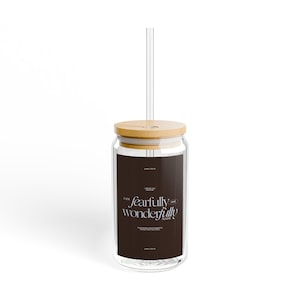 Puede incluir: Un vaso de vidrio transparente con tapa de bambú y pajita transparente. El vaso tiene una etiqueta marrón oscuro con el texto "I AM fearfully and wonderfully made" en escritura blanca. Diseñado para bebidas frías.