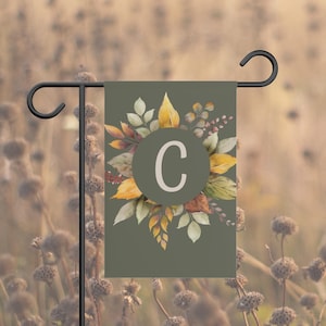 Peut inclure: Un drapeau de jardin rectangulaire avec un fond vert olive et un cercle vert foncé central contenant la lettre C. Autour du cercle se trouve une composition de feuilles d'automne aux tons jaunes, orange et bruns, style aquarelle.