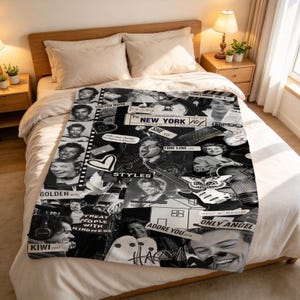 May include: A black and white fleece blanket featuring a collage of Harry Styles photographs, song titles like Golden, Kiwi, Adore You, and text including New York, Treat People With Kindness, and Fine Line, spread across a bed with white bedding.
