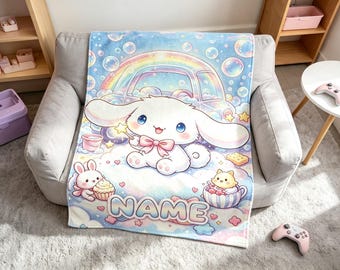 Könnte beinhalten: Eine weiche Fleecedecke mit einem weißen Cartoon-Hasen mit langen Ohren, einer rosa Schleife und einem Sternenstab. Das Design zeigt einen Regenbogen, Seifenblasen, einen kleineren Hasen mit Cupcake, eine Katze in einer Teetasse und den Schriftzug NAME.