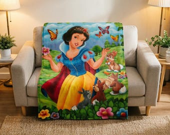 Könnte beinhalten: Eine rechteckige Fleecedecke mit einer farbenfrohen Illustration von Schneewittchen mit blauem Oberteil, gelbem Rock und rotem Umhang, umgeben von braunen Kaninchen, Schmetterlingen und verschiedenen Blumen in einer grünen Waldlandschaft.