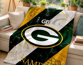 Könnte beinhalten: Eine Plüschdecke mit Green Bay Packers-Motiv, einem großen zentralen G-Logo, Footballhelm-Grafiken sowie dem Text GB und NAME. Das Design zeigt diagonale Streifen in Dunkelgrün, Gold und Weiß mit kleinen Sternakzenten.