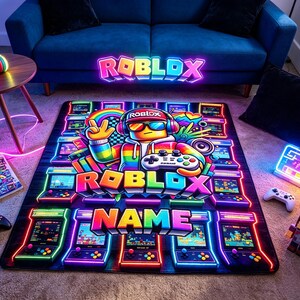 May include: A rectangular area rug featuring a vibrant Roblox-themed graphic with a central character wearing headphones and sunglasses, surrounded by neon-style arcade cabinets, the word Roblox, and a customizable name section in colorful block letters.