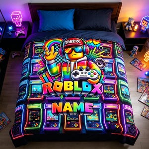 May include: A vibrant bed comforter featuring a central character wearing headphones and sunglasses, holding a game controller. The design includes neon-coloured arcade machines, the text ROBLOX, and a customisable NAME section in a bold, colourful font.