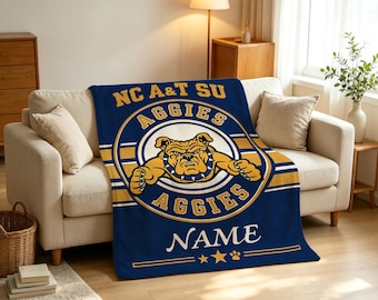 Könnte beinhalten: Eine marineblaue Fleecedecke mit dem NC A&T SU Aggies-Logo und einer zentralen Bulldoggen-Illustration. Das Design umfasst goldene und weiße kreisförmige Akzente, den Schriftzug AGGIES, ein anpassbares Namensfeld sowie Stern- und Pfoten-Symbole.