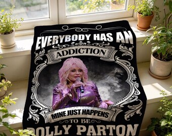 Könnte beinhalten: Eine schwarze Wohndecke mit einem zentralen Fotoporträt von Dolly Parton, die ein Mikrofon hält. Der Text lautet: EVERYBODY HAS AN ADDICTION MINE JUST HAPPENS TO BE DOLLY PARTON. Das Design enthält verzierte weiße Schnörkel-Umrandungen.