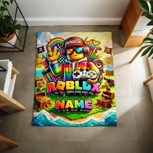 May include: A rectangular blanket featuring a colorful Roblox-themed graphic. A character wearing headphones, sunglasses, and a rainbow hoodie holds a game controller. The design includes treasure chests, parrots, cannons, and the text Roblox and Name.