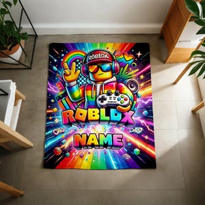 May include: A rectangular blanket featuring a vibrant rainbow-colored graphic of a character wearing headphones, sunglasses, and a cap, holding a game controller. The design includes the text ROBLOX and NAME, surrounded by colorful light streaks.