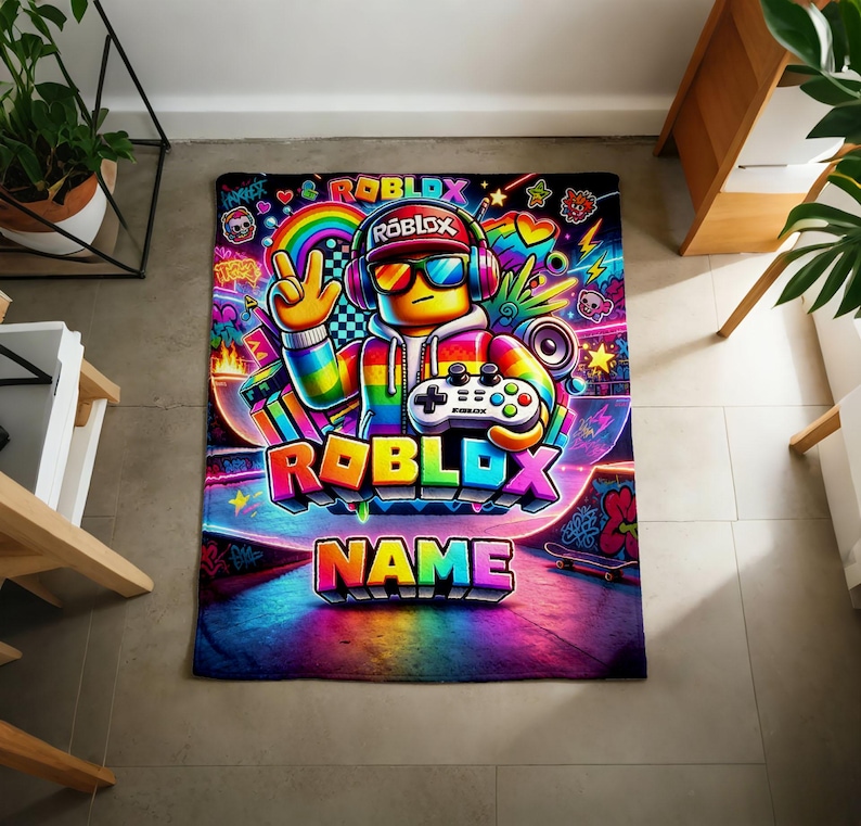 May include: A rectangular blanket featuring a vibrant, multi-colored graphic of a Roblox character wearing headphones and sunglasses, holding a game controller. The design includes the text ROBLOX and NAME, surrounded by neon rainbows, stars, and graffiti.