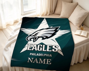 Könnte beinhalten: Eine dunkel-petrolfarbene Fleecedecke mit einem großen weißen Sternmotiv und dem Adlerkopf-Logo der Philadelphia Eagles in der Mitte. Der Schriftzug EAGLES, PHILADELPHIA und NAME ist in weißen Buchstaben unter dem Stern zu sehen.