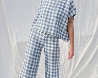 May include: A blue and white gingham patterned top and wide-leg pants set. The top has a relaxed fit and short sleeves. The pants have a high waist and a wide leg.