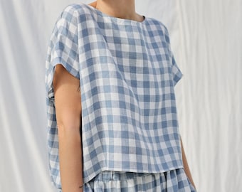 Op de afbeelding: Een blauwe en witte gingham top en rok set. De top heeft een ontspannen pasvorm en korte mouwen. De rok heeft een hoge taille en een zwierige silhouet.