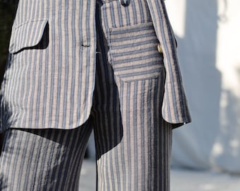 May include: A striped linen pantsuit in shades of blue and white. The pants have a wide leg and a patch pocket on the right side.