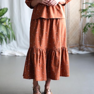 May include: A long rust-colored skirt with a floral print and a ruffled hem.