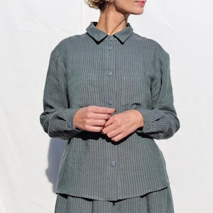 Puede incluir: Una camisa de manga larga a rayas en azul y verde. La camisa tiene un cuello abotonado y un corte holgado.