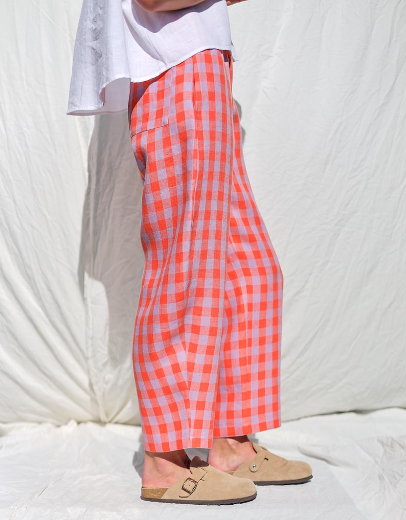 May include: Wide-leg pants in a pink and orange gingham pattern. The pants are cropped and have a relaxed fit.