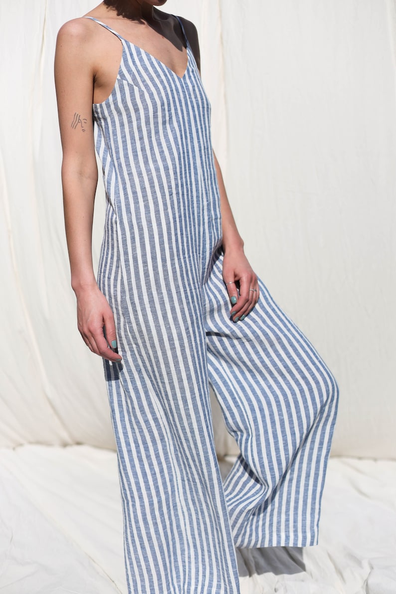 Puede incluir: Una mujer con un mono a rayas azul y blanco. El mono tiene tirantes finos y cuello en V.