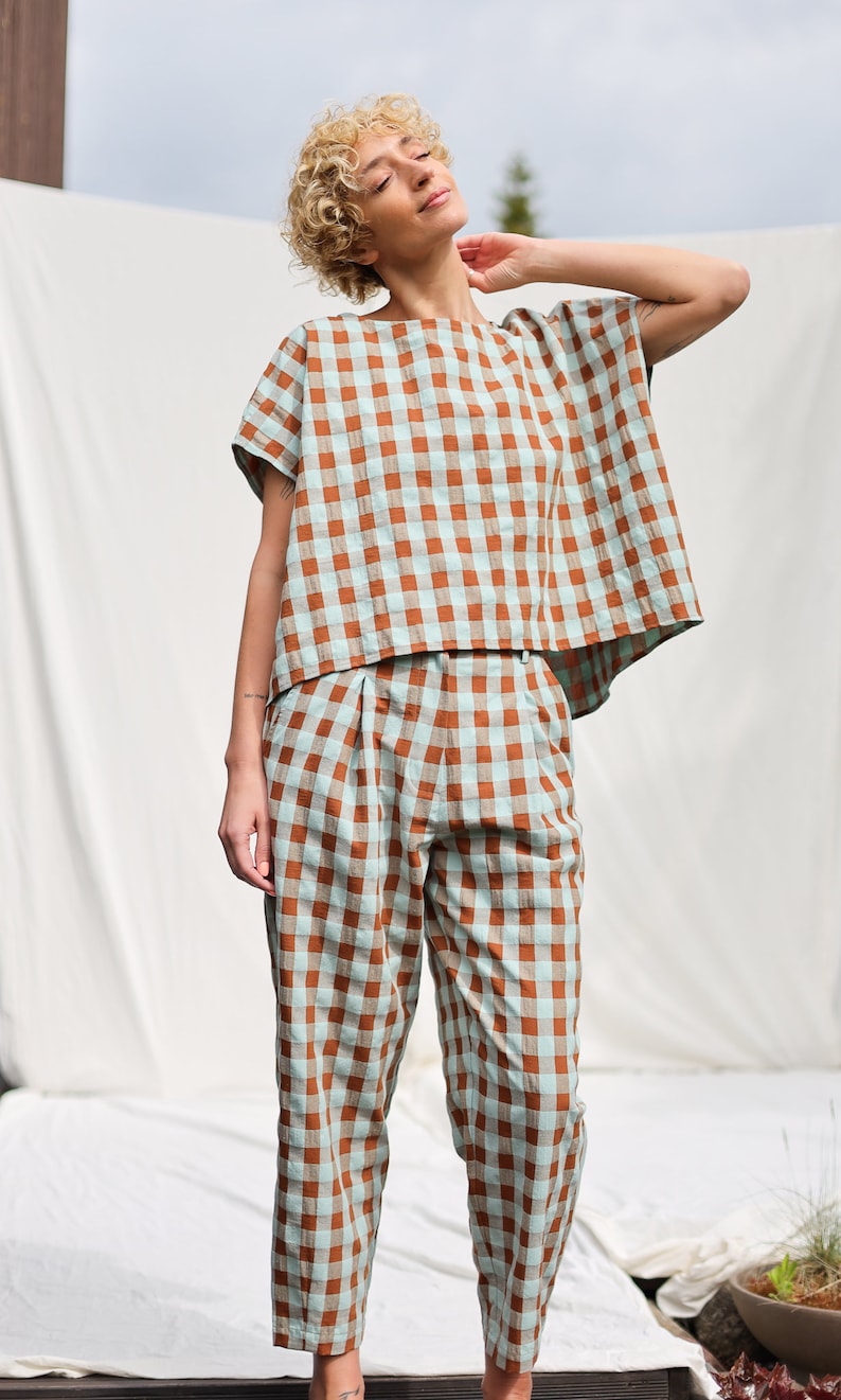 May include: A woman wearing a brown and blue gingham top and matching pants. The top has a relaxed fit and short sleeves. The pants are cropped and have a pleated waistband.