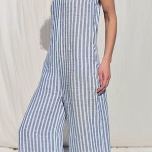 Puede incluir: Un mono de lino a rayas azules y blancas con tirantes finos. El mono tiene cuello en V y piernas anchas.