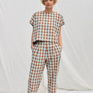 May include: A brown and light blue gingham patterned top and pants set. The top has short sleeves and a relaxed fit. The pants have a high waist and a straight leg.