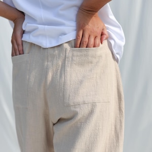 Puede incluir: Pantal&oacute;n de lino beige con dos grandes bolsillos de parche en la parte posterior. El pantal&oacute;n tiene un corte holgado y una pierna recta.