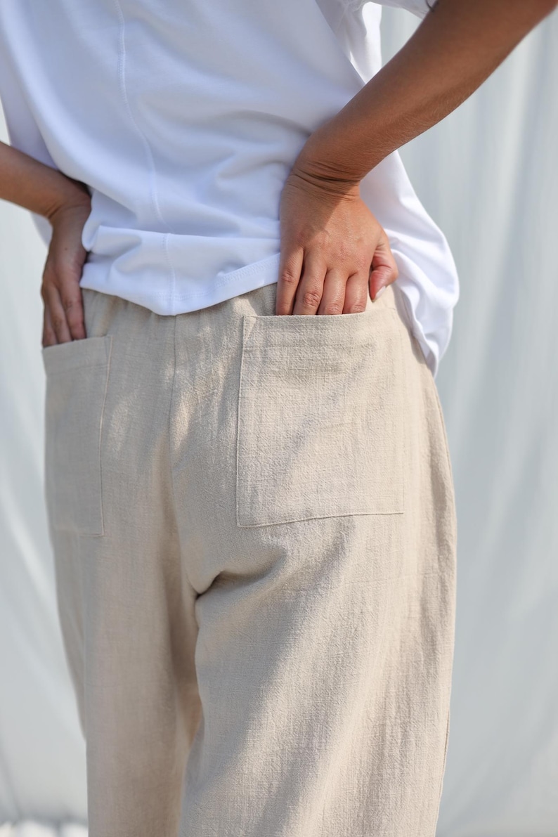 Puede incluir: Pantal&oacute;n de lino beige con dos grandes bolsillos de parche en la parte posterior. El pantal&oacute;n tiene un corte holgado y una pierna recta.