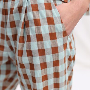 May include: Brown and light blue checkered pants with a pleat in the front. The pants have a pocket on the side.