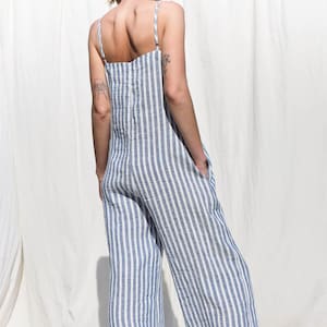 Puede incluir: Un mono de lino a rayas azules y blancas con piernas anchas. El mono tiene tirantes finos y un ajuste holgado.
