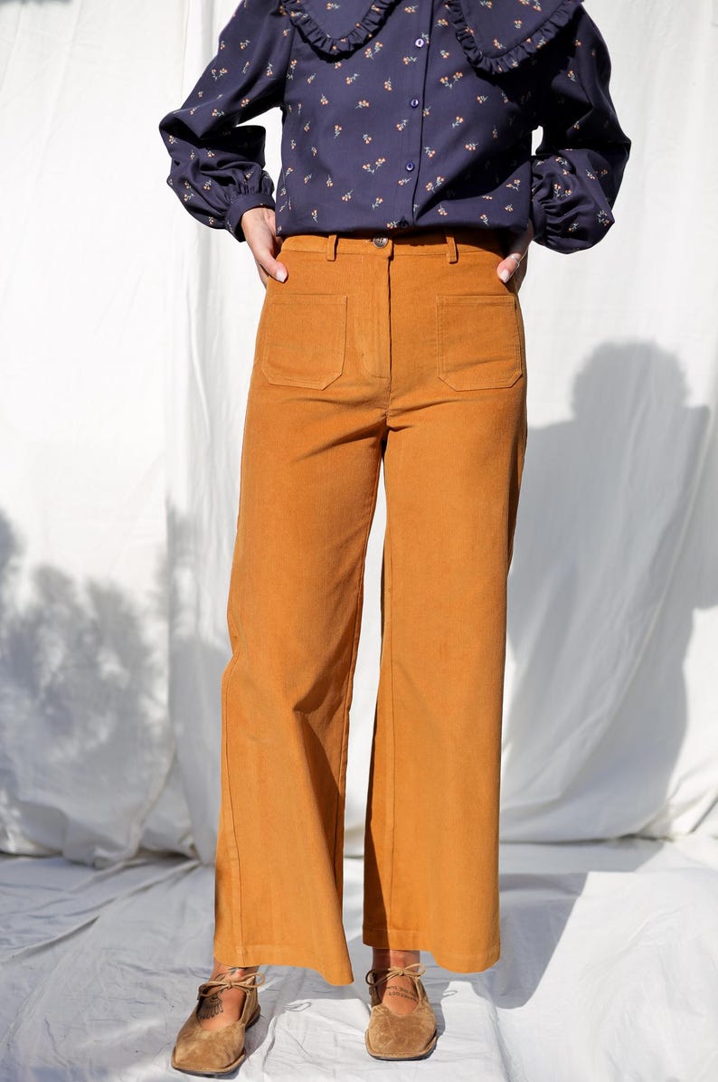 May include: A pair of wide-leg corduroy pants in a burnt orange color. The pants have a high waist and large pockets on the front.