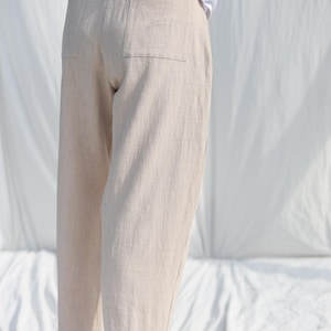 Puede incluir: Un pantal&oacute;n de lino beige con un bolsillo trasero. El pantal&oacute;n es corto y tiene un corte holgado.