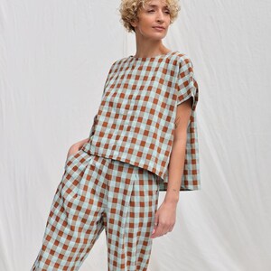 May include: A brown and light blue gingham patterned top and pants set. The top has a relaxed fit and short sleeves. The pants have a high waist and a straight leg.