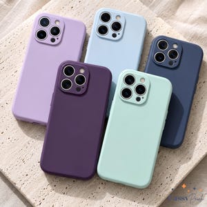 May include: Five silicone smartphone cases in lavender, light blue, dark blue, deep purple, and mint green. Each case features a square camera cutout with three circular lens openings and a small flash hole, arranged in a cluster on the back.