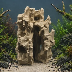 May include: A beige, porous aquarium rock sculpture featuring a tall, craggy structure with multiple natural openings and crevices. The rock has a rough, uneven texture and stands upright, creating a cave-like appearance for aquatic environments.