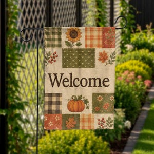 May include: A rectangular garden flag featuring a patchwork design of autumn-themed patterns including sunflowers, pumpkins, berries, and leaves. The word Welcome is printed in dark brown letters across the center of the beige fabric background.