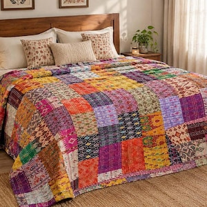 Puede incluir: Una colcha rectangular con un diseño de patchwork compuesto por numerosos cuadrados de tela en colores vibrantes que incluyen naranja, morado, amarillo, rosa y verde. La colcha muestra varios patrones geométricos y florales complejos.