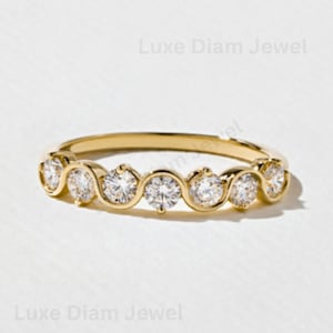 Peut inclure: Une bague en or jaune ornée de sept diamants blancs ronds taille brillant, sertis dans une structure métallique ondulée continue. La bague présente une finition polie et le texte Luxe Diam Jewel est visible en arrière-plan.