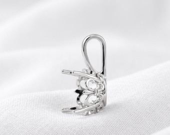 Könnte beinhalten: Eine silberfarbene Anhängerfassung aus Metall mit einer dekorativen Filigran-Galerie im Fleur-de-Lis-Stil und einer integrierten vertikalen Öse an der Oberseite, die zur Aufnahme eines Edelsteins in einer Krappenfassung dient.