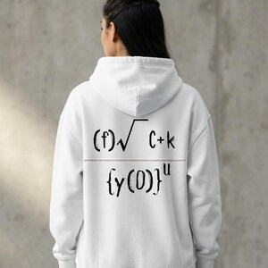 May include: A white hooded sweatshirt featuring a black mathematical equation printed on the back. The design displays the expression (f)√C+k over {y(0)}u in a hand-drawn style font. The garment includes a hood, long sleeves, and a ribbed hem.