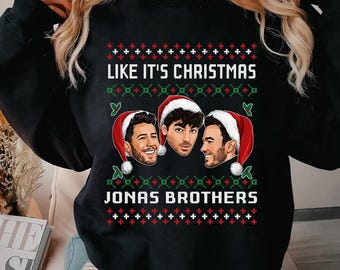 May include: A black long-sleeve sweatshirt featuring a graphic print of the Jonas Brothers wearing Santa hats. The text reads "LIKE IT'S CHRISTMAS" and "JONAS BROTHERS" in white, surrounded by red and green festive patterns. The text "Size up for oversize look" is visible.