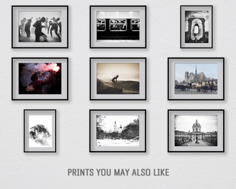 May include: A wall gallery of nine black and white framed photographs. The photos include a group of people dancing, a subway car interior, a brick archway, a person holding a red flare, a surfer on a wave, a view of Notre Dame Cathedral in Paris, a tree with a cloudy background, a snowy landscape with a church, and a view of a building with a dome.
