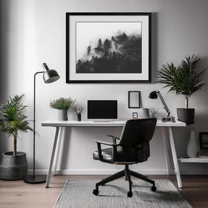 Photographie en noir et blanc d'une forêt enveloppée de brume. Les arbres apparaissent à travers un voile de brouillard, créant une ambiance apaisante et mystérieuse.