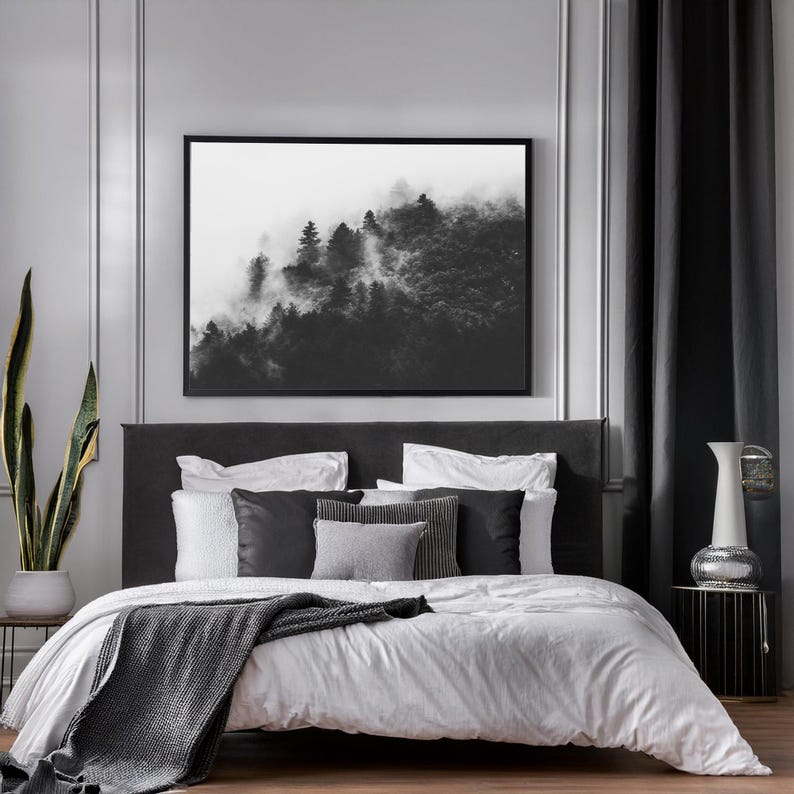 Photographie en noir et blanc d'une forêt enveloppée de brume. Les arbres apparaissent à travers un voile de brouillard, créant une ambiance apaisante et mystérieuse.