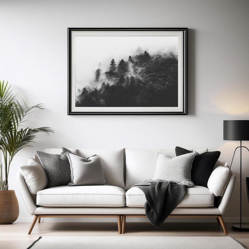 Photographie en noir et blanc d'une forêt enveloppée de brume. Les arbres apparaissent à travers un voile de brouillard, créant une ambiance apaisante et mystérieuse.