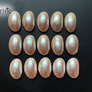 May include: A collection of 15 oval-shaped iridescent white mother of pearl cabochons. The cabochons are smooth and have a pearlescent sheen.