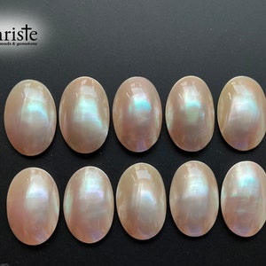 Puede incluir: Diez gemas ovaladas e iridiscentes con brillo nacarado. Las piedras son de color rosa suave con destellos azules y verdes. Están dispuestas en dos filas de cinco sobre un fondo oscuro. Se observa el texto "Christe beads & gemstone".