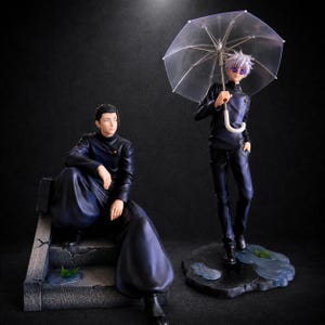 May include: Two anime-style figures in dark uniforms. One figure with dark hair sits on stone steps. The other figure with white hair stands holding a clear umbrella, wearing round purple sunglasses, positioned on a base with blue puddle details.