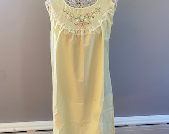 May include: A pale yellow sleeveless nightgown with a white lace trim and embroidered floral design. The neckline is round and the gown has a straight silhouette.