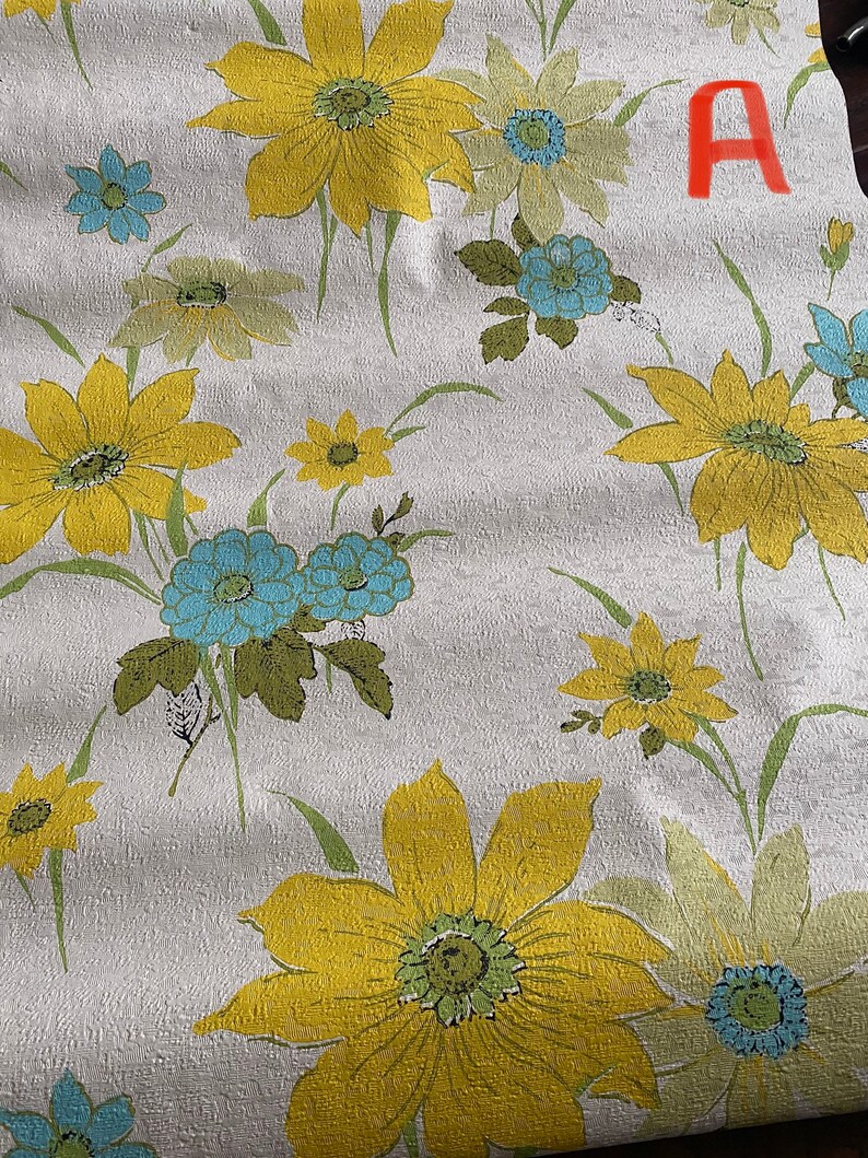 May include: White wallpaper with a floral pattern featuring yellow, green, and blue flowers. The flowers are stylized and have a retro look. The wallpaper has a textured surface.